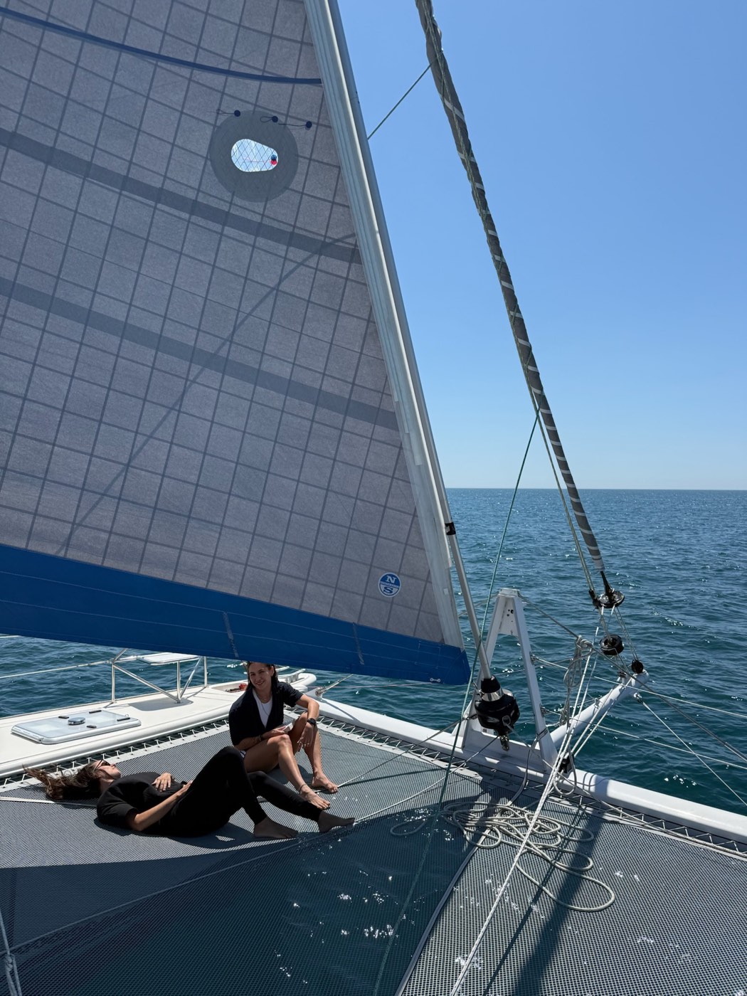 Des équipiers détendus sur le trampoline de Little Cloud, notre catamaran Catana 431, sous voiles